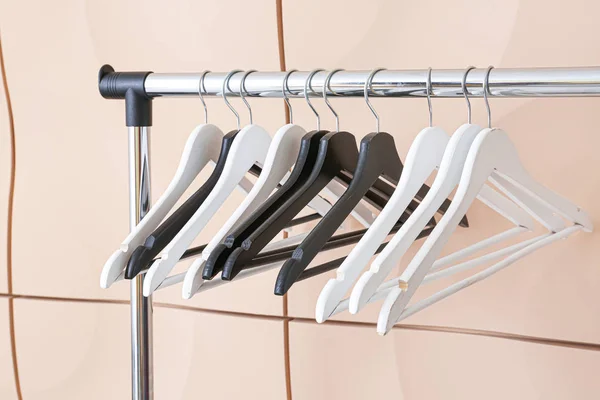 Rack with clothes hangers against light wall — Stock Photo, Image