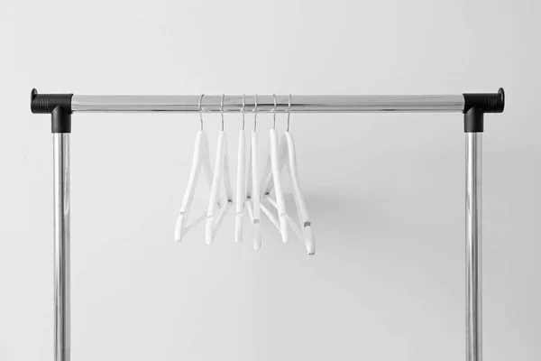 Rack with clothes hangers on light background — Stock Photo, Image
