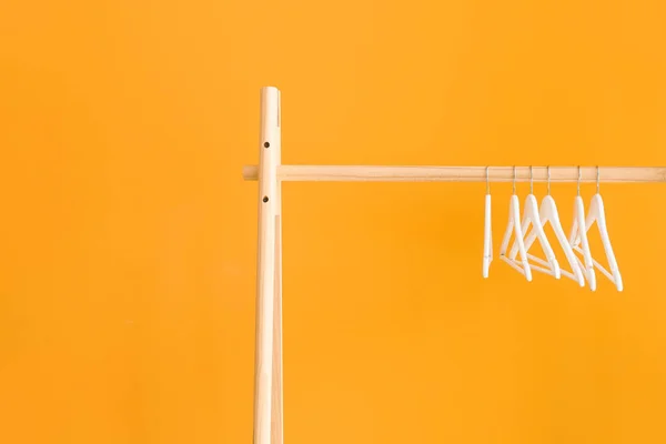 Стойка с вешалками для одежды на цветном фоне — стоковое фото