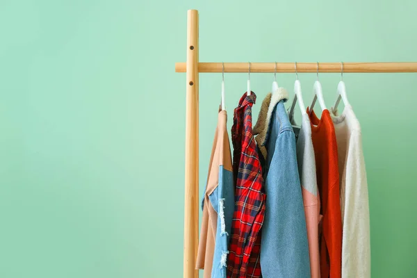 Bastidor con ropa colgante sobre fondo de color — Foto de Stock