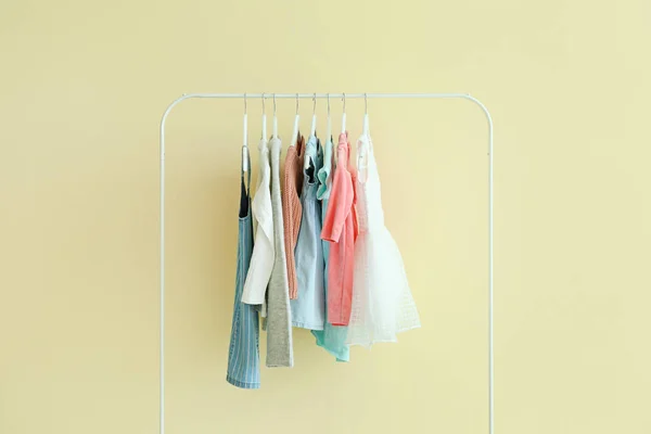 Stojak z wiszącymi ubraniami na kolorowym tle — Zdjęcie stockowe