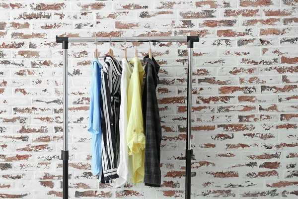 Rack with hanging clothes near brick wall — Stock Photo, Image