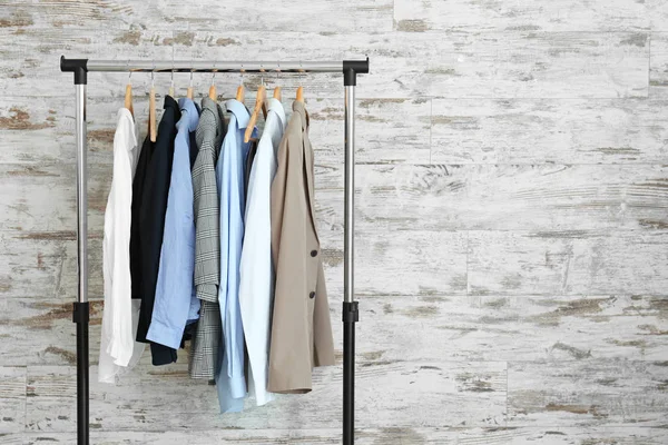 Rack com roupas penduradas perto da parede de madeira — Fotografia de Stock