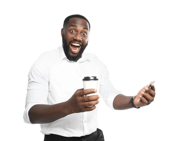 Empresário afro-americano animado com xícara de café e telefone celular em fundo branco — Fotografia de Stock