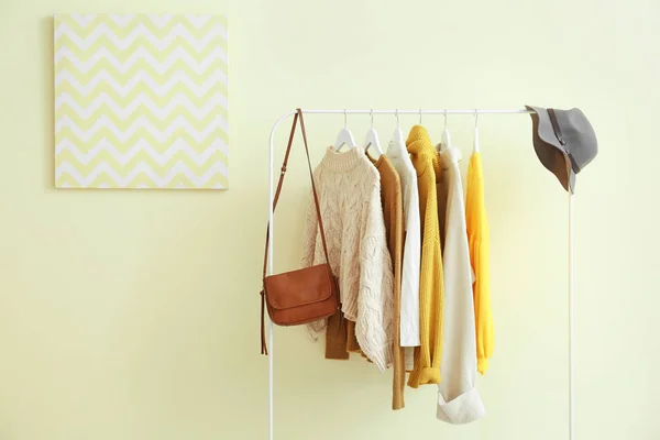 Rack with hanging clothes on color background — Stock Photo, Image