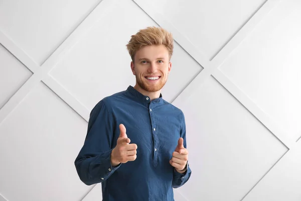 Portrait of young man pointing at viewer on grey background — Stock Photo, Image