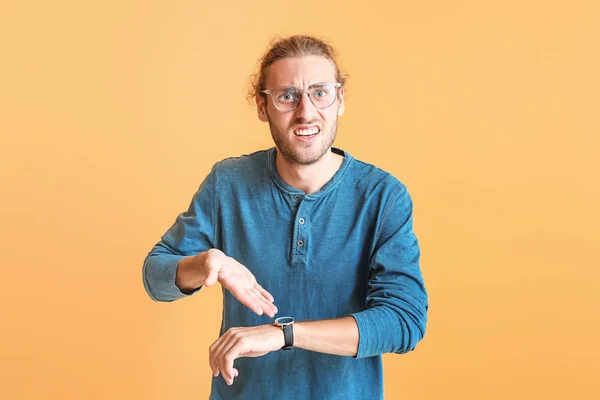 Stressed young man with watch on color background — Stock Photo, Image