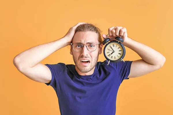 Stressed man with alarm clock on color background — Stock Photo, Image