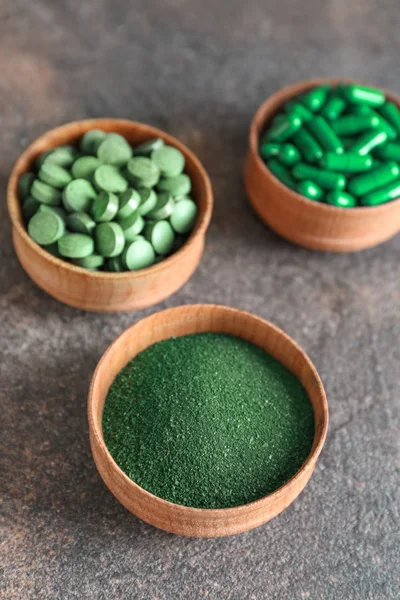 Bowls with spirulina powder and pills on grey background — Stock Photo, Image