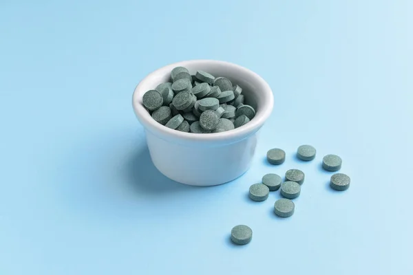 Bowl with spirulina pills on color background — Stock Photo, Image