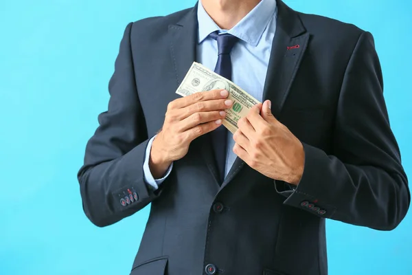 Empresario poniendo soborno en el bolsillo contra el fondo de color. Concepto de corrupción — Foto de Stock