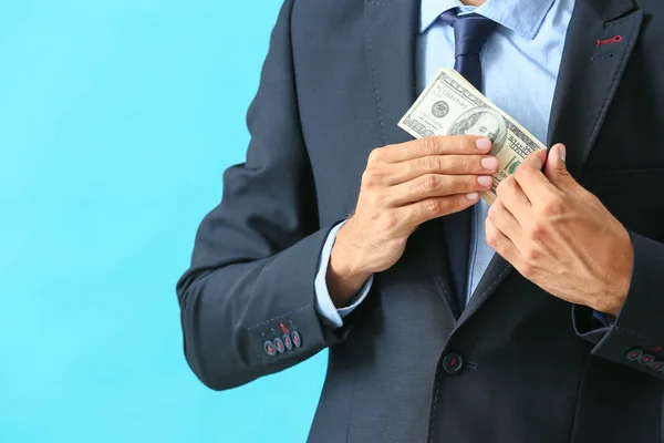 Businessman putting bribe in pocket against color background. Concept of corruption — Stock Photo, Image