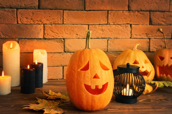 Halloween pumpkins with candles on wooden table near brick wall — Stock Photo, Image