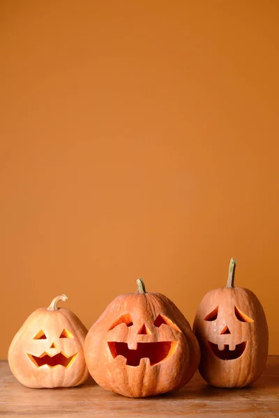 Halloween pumpkins on wooden table against color background — Stock Photo, Image