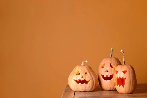 Calabazas de Halloween sobre mesa de madera contra fondo de color —  Fotos de Stock