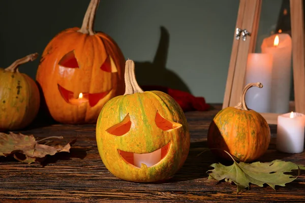 Geschnitzte Kürbisse für Halloween und Kerzen auf Holztisch — Stockfoto