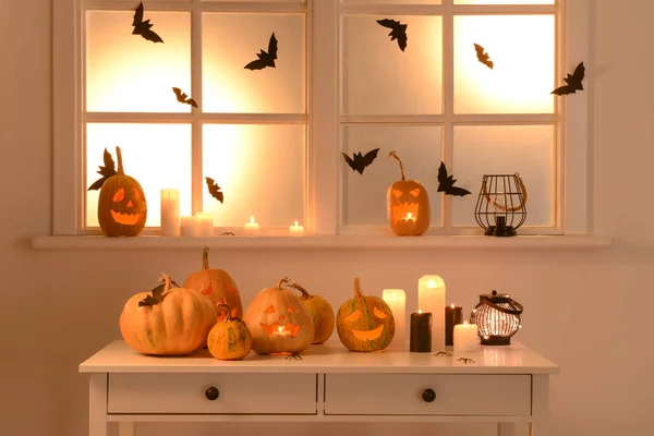 Halloween pumpkins and candles on table near window — Stock Photo, Image