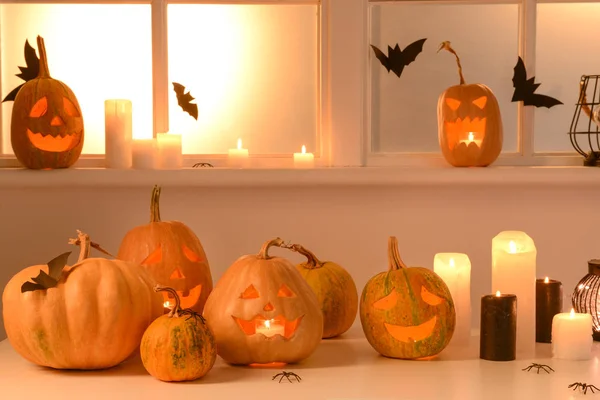 Halloween-Kürbisse und Kerzen auf dem Tisch am Fenster — Stockfoto