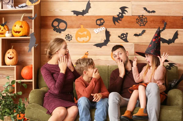 Divertida familia sentada en la habitación decorada para Halloween —  Fotos de Stock