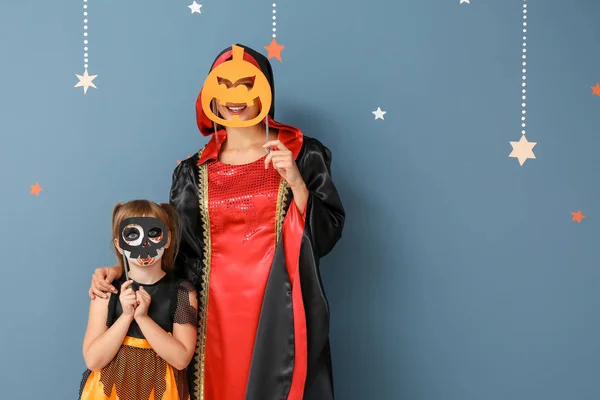 Moeder met kleine dochter in Halloween kostuums op kleur achtergrond — Stockfoto