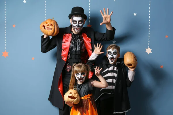 Padre con niños en disfraces de Halloween y con calabazas sobre fondo de color —  Fotos de Stock