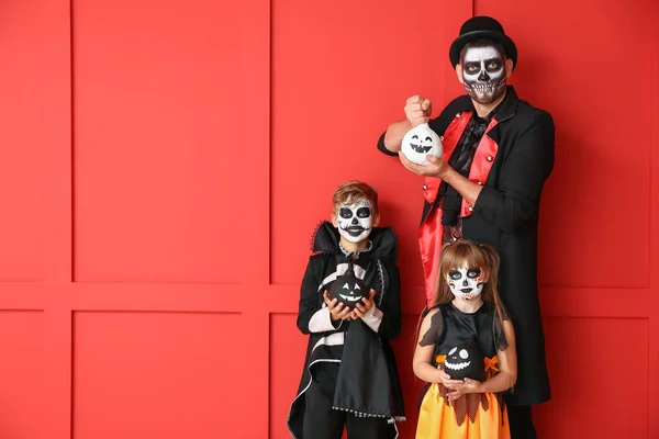 Padre con niños en disfraces de Halloween y con calabazas sobre fondo de color —  Fotos de Stock