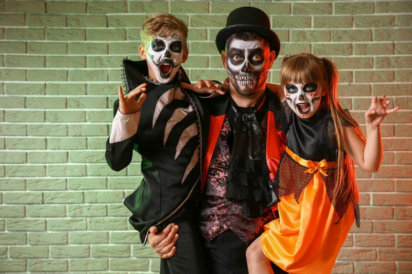 Pai com crianças em trajes de Halloween no fundo de tijolo — Fotografia de Stock