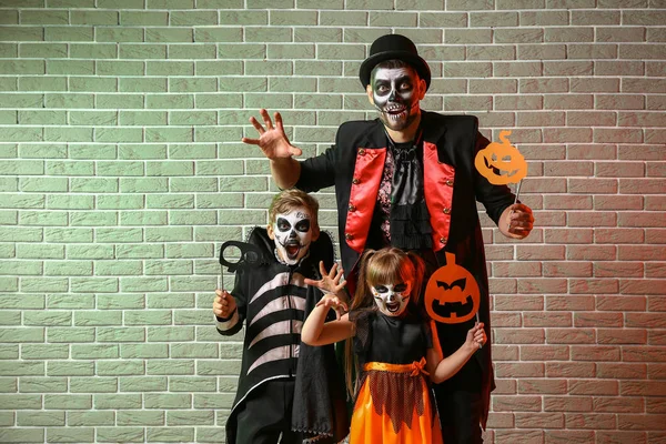 Vater mit Kindern in Halloween-Kostümen auf Backstein-Hintergrund — Stockfoto