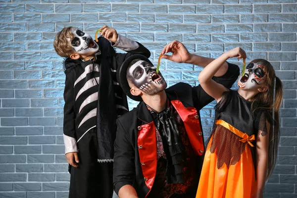 Cadılar Bayramı kostümlü baba tuğla arka planda jöle solucanı yiyor.