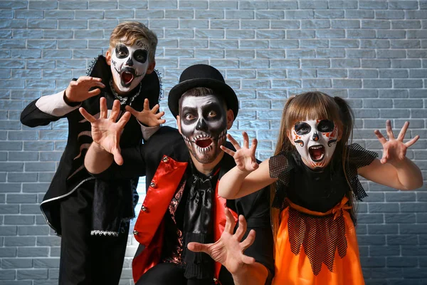 Pai com crianças em trajes de Halloween no fundo de tijolo — Fotografia de Stock