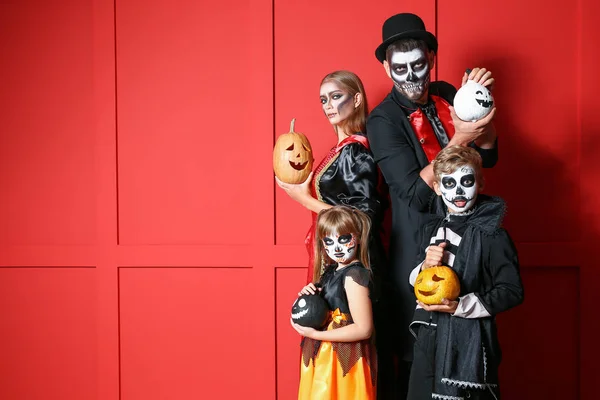 Rodzina w kostiumach Halloween i z dyniami na tle koloru — Zdjęcie stockowe