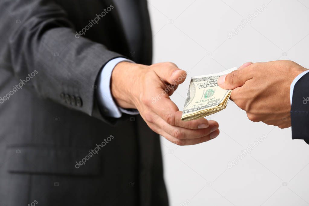 Businessman taking bribe against light background
