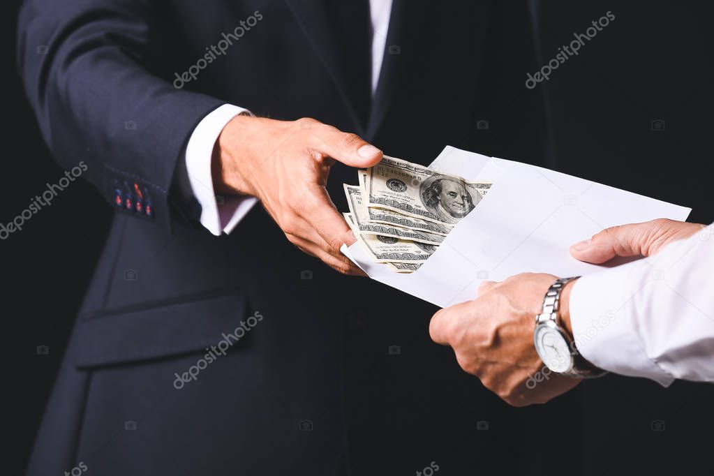 Businessman taking bribe against dark background, closeup