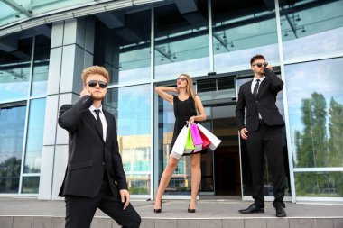 Alışveriş merkezinin yakınından alışveriş yapan korumaları olan ünlü biri.