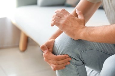 Genç adam closeup evde, diz ağrısı muzdarip