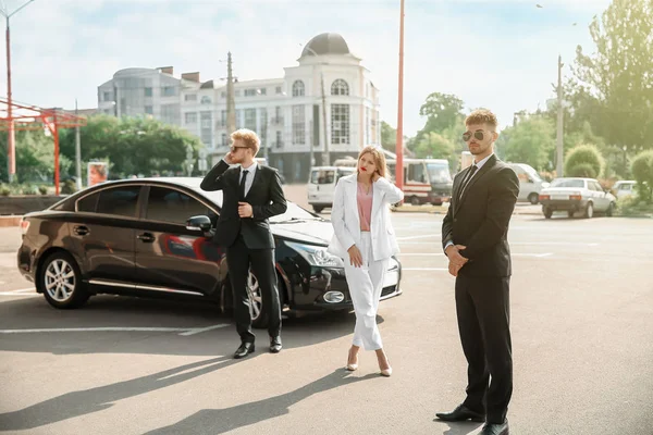 Young celebrity with bodyguards near car