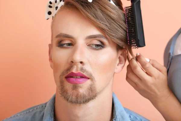 Girlfriend doing hair of young transgender woman on color background, closeup — Stock Photo, Image