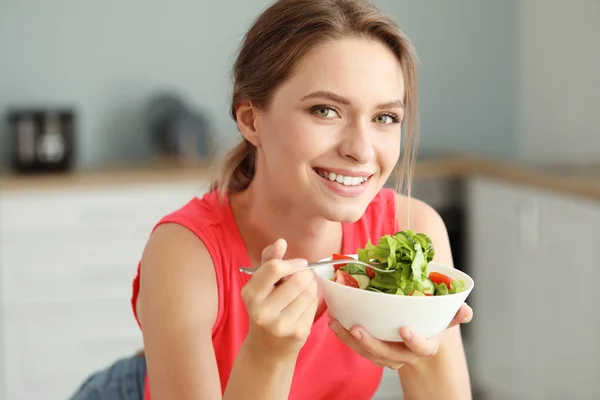 Mujer joven comiendo ensalada de verduras saludables en la cocina. Concepto de dieta —  Fotos de Stock