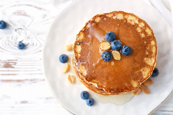 Piring dengan pancake lezat dan blueberry di atas meja putih — Stok Foto