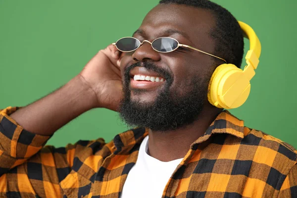 Handsome African-American man listening to music on color background — Stock Photo, Image
