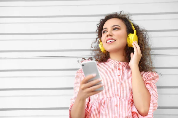 Piękna Afroamerykanka z telefonem komórkowym słuchająca muzyki na świeżym powietrzu — Zdjęcie stockowe