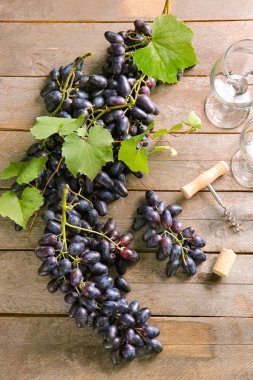 Tahta masada şarap kadehli tatlı üzümler.