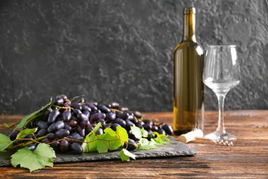 Tahta masada tatlı üzümlü bir tabak ve bir şişe şarap.