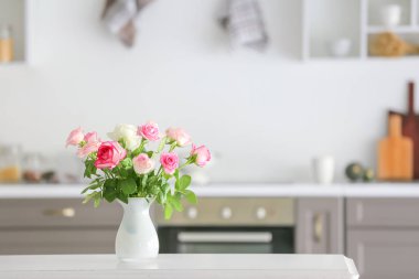 Mutfaktaki masada vazoda güzel gül çiçekleri.
