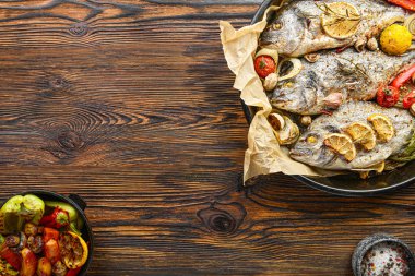 Ahşap arka planda sebzeli dorado balığı.