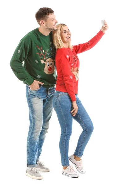 Szczęśliwa para w świątecznych swetrach robi selfie na białym tle — Zdjęcie stockowe