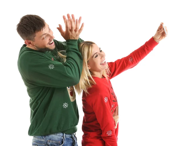 Happy couple in Christmas sweaters taking selfie on white background — Stock Photo, Image