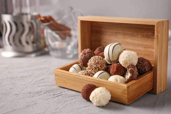 Box with tasty sweet truffles on grey table