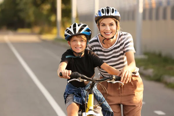 Mãe ensinando seu filho a andar de bicicleta ao ar livre — Fotografia de Stock