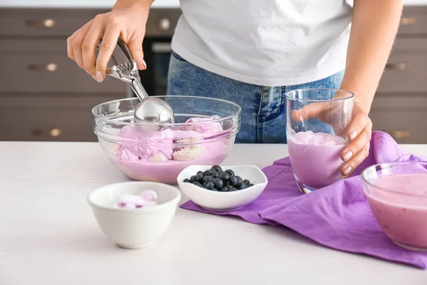 부엌에 있는 유리에 맛있는 블루베리 아이스크림을 넣는 여자 — 스톡 사진